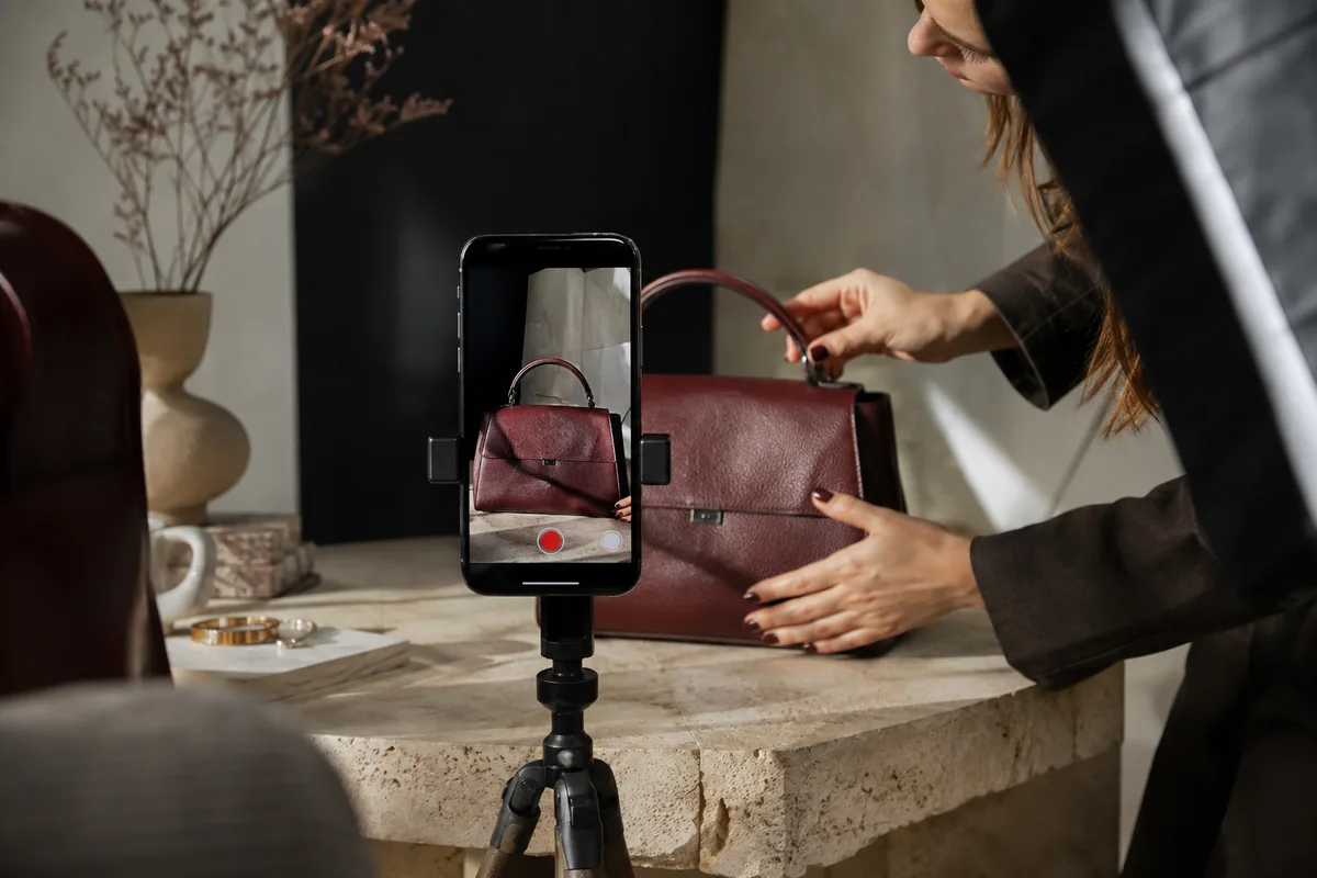 Ein Produktvideo entsteht: Smartphone-Aufnahme einer burgunderfarbenen Tasche